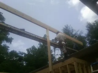 Carpenter setting a ridge beam over a new addition frame — Ice Dam Removal by Roofing Brothers in Harvey
