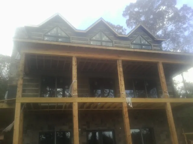 Dormers and porch framing on a large log home under construction — Roof Coating work by our crew in Harvey