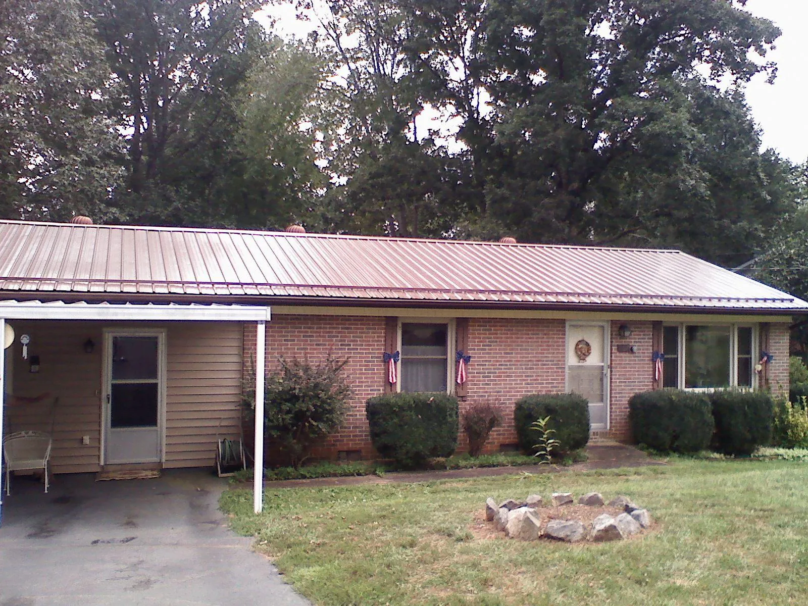 Bronze metal roof and carport on a brick ranch home — Roof Repair work by our crew in Harvey