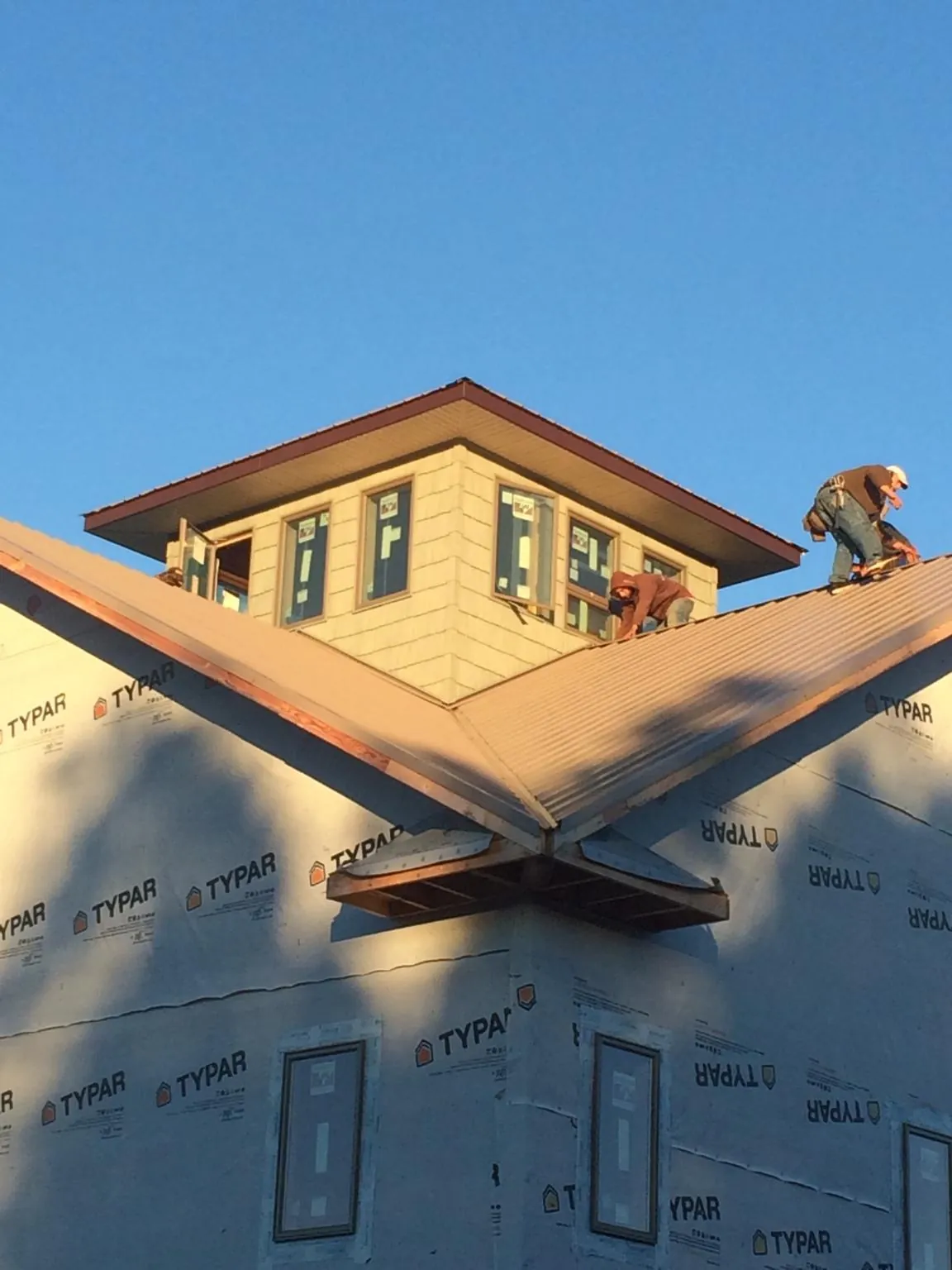 Roofers working around a rooftop cupola on a new metal roof at sunset — Roof Waterproofing in Harvey by Roofing Brothers